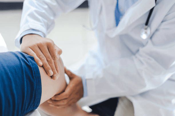Specialist examining a patient's knee to assess arthritis before knee replacement