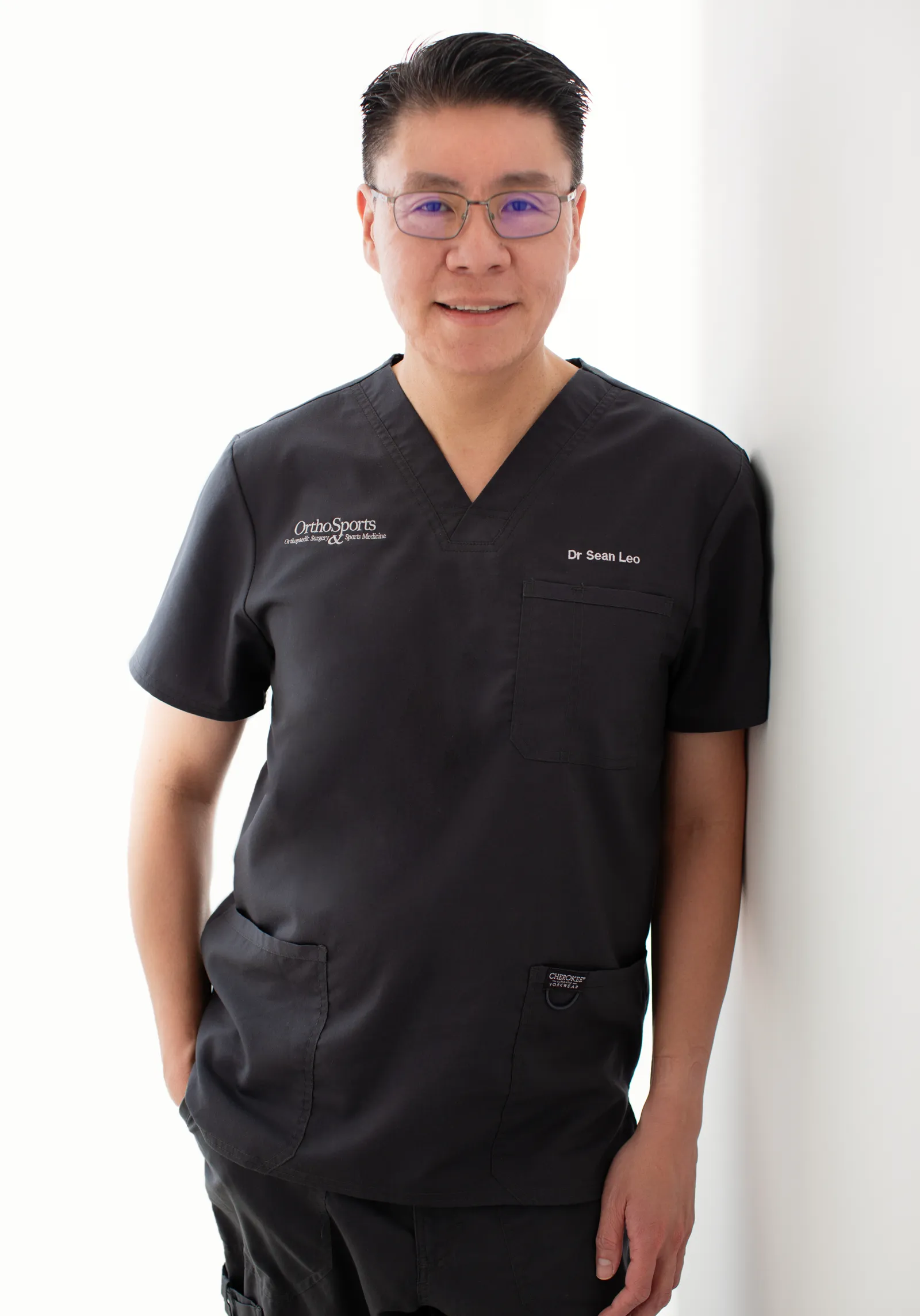 Dr Sean Leo standing in clinical scrubs against a plain wall