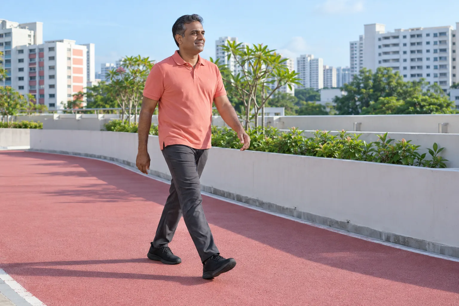 An Indian man walks along a rooftop running track.