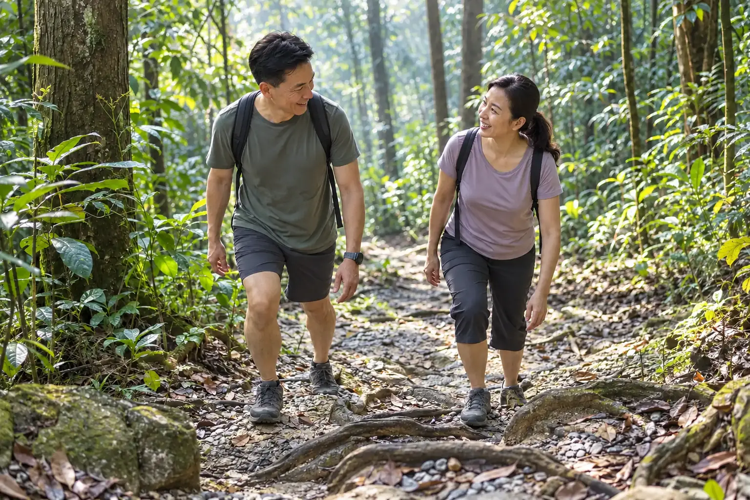 A couple walks uphill on a gravel forest trail while stepping over exposed roots.