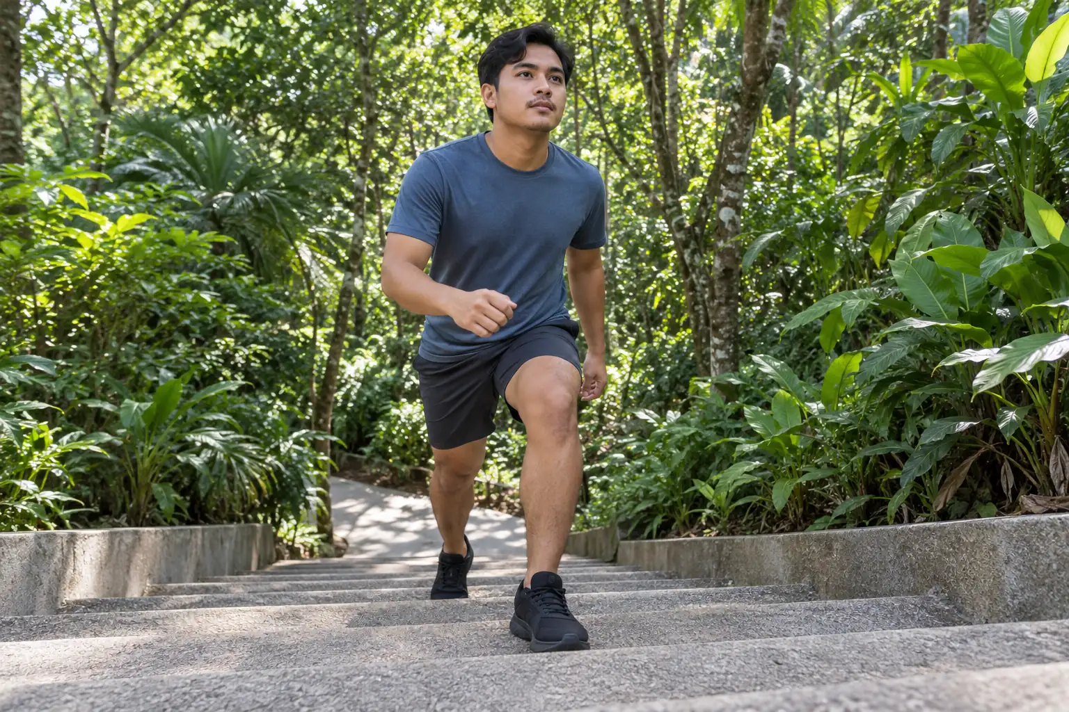 A young man climbs a broad park staircase with his leading knee bent.