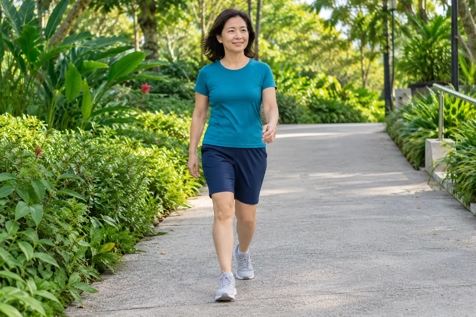 A woman walks down a gentle paved slope in a neighbourhood park with her knees visible.