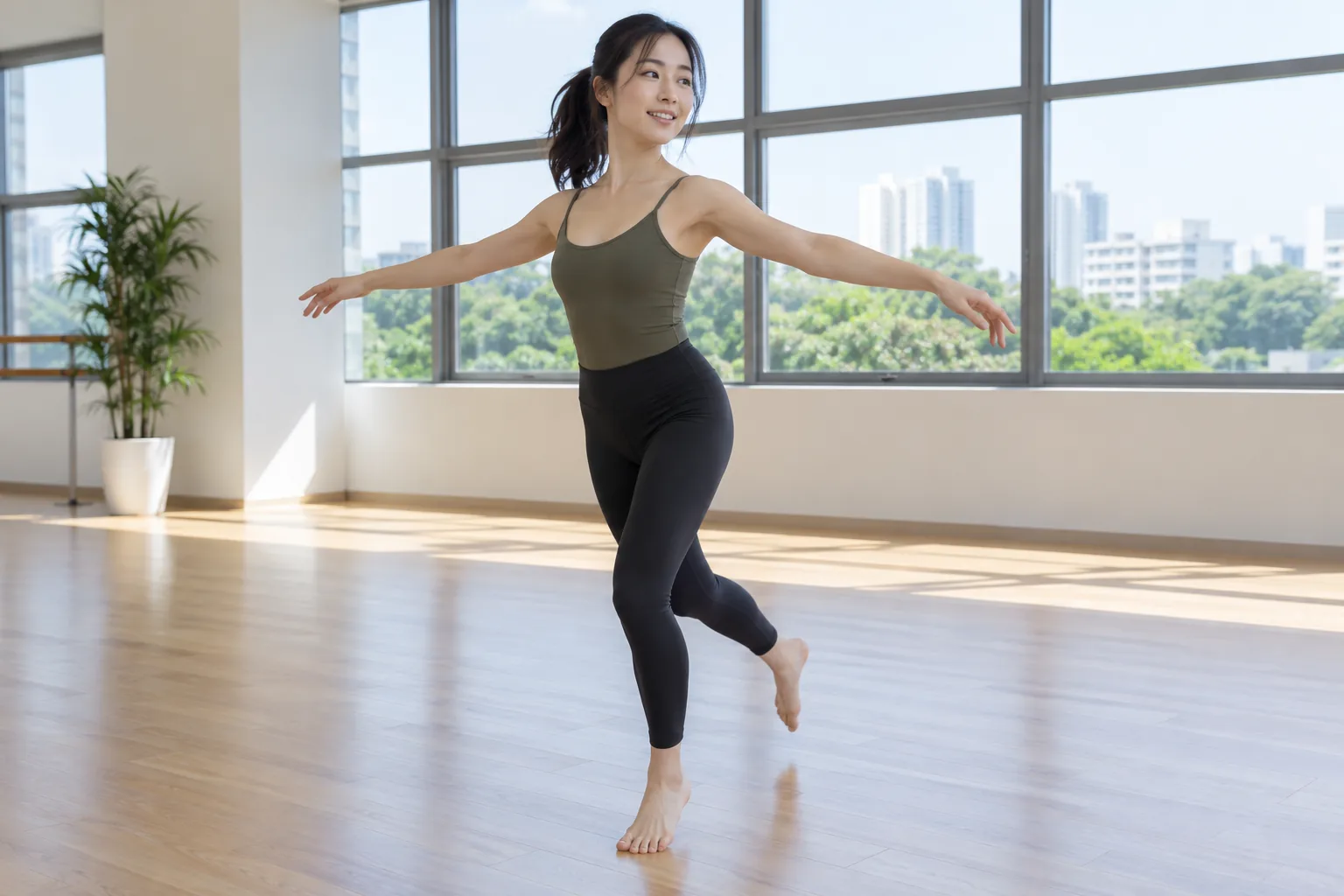 A young woman turns on one foot in a dance studio with her standing knee slightly bent.