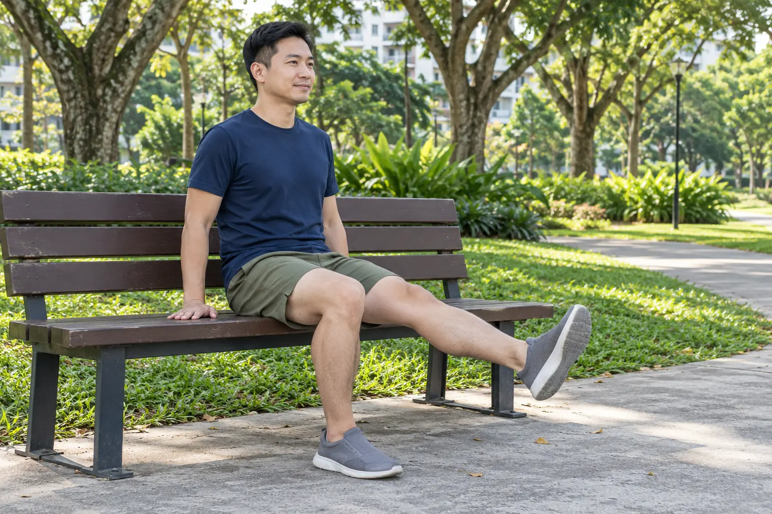 A man sits on a park bench and gently straightens one knee in front of him.