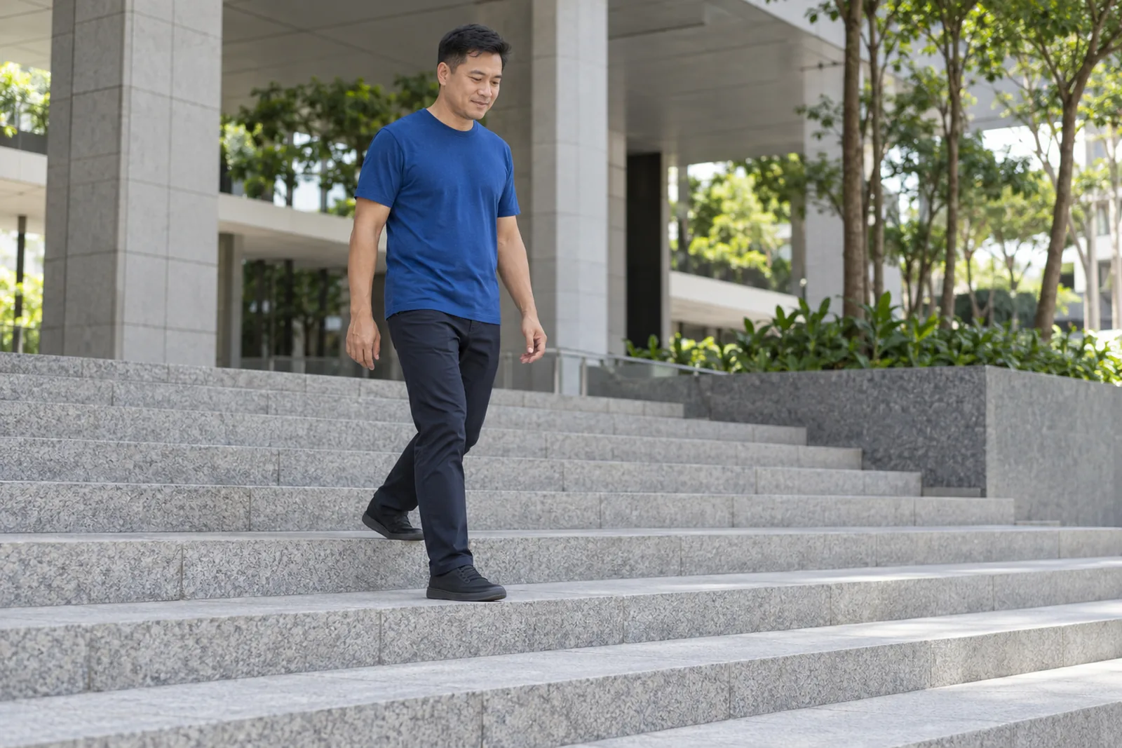 A man walks down broad granite steps at a controlled pace outside a civic building.