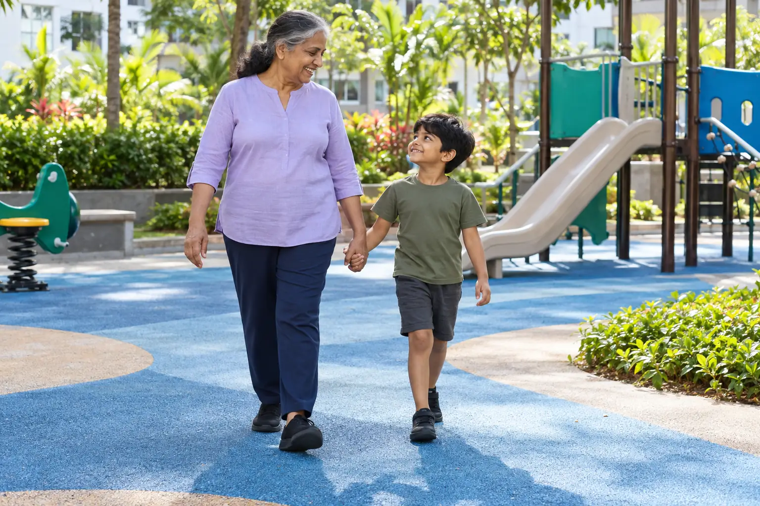 An Indian grandmother walks hand in hand with her grandchild in a playground.